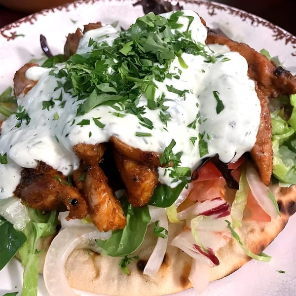 Mediterranean chicken gyro with white sauce and fresh parsley on a flatbread.